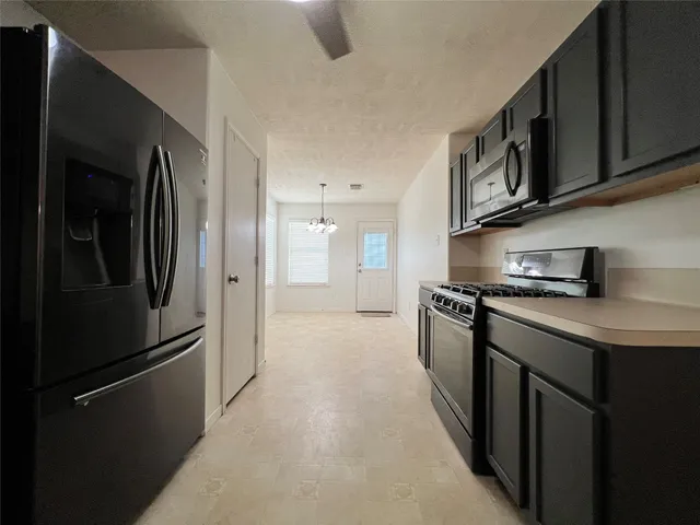 a kitchen with stainless steel appliances granite countertop a refrigerator a stove and a sink