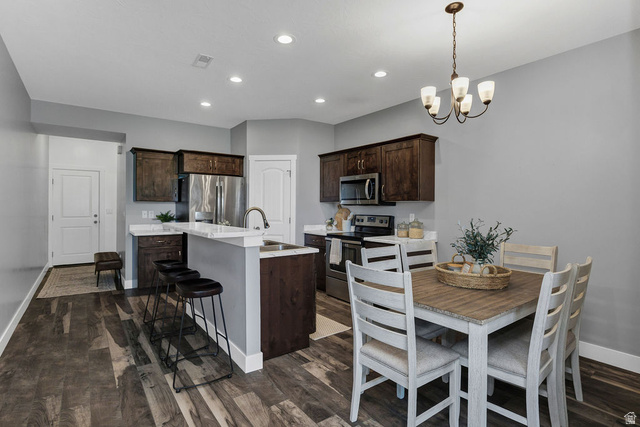 2483 South 1296th Street West Logan, UT 84321 - Photo 6 of 45 Open-concept kitchen and dining area featuring wood-finish flooring, dark wood cabinetry, stainless steel appliances, and recessed lighting