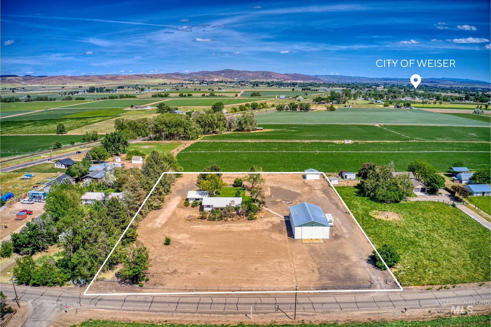 748 Pringle Road Weiser, ID 83672 - Photo 45 of 47 Expansive agricultural property featuring a primary residence with a light-colored roof, a large metal-sided outbuilding, and significant undeveloped land