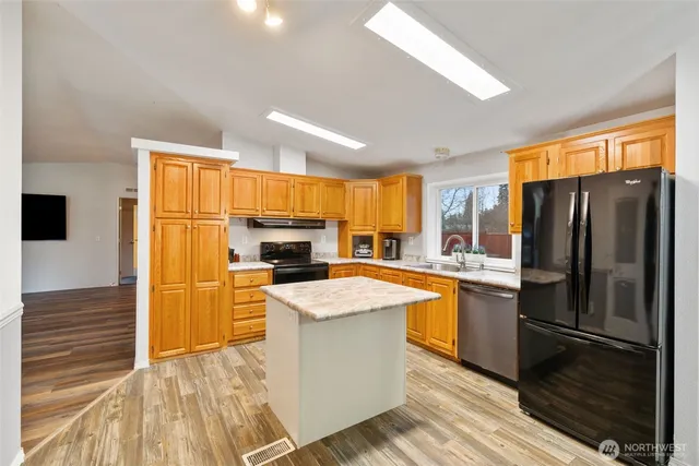 a kitchen with stainless steel appliances granite countertop a refrigerator a stove top oven a sink and dishwasher