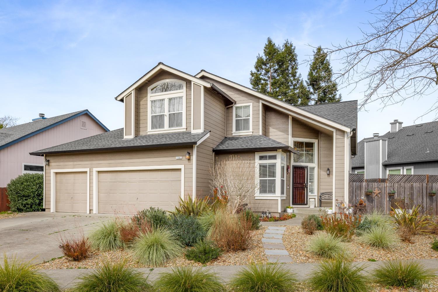 a view of a yard in front of a house with plants and large tree