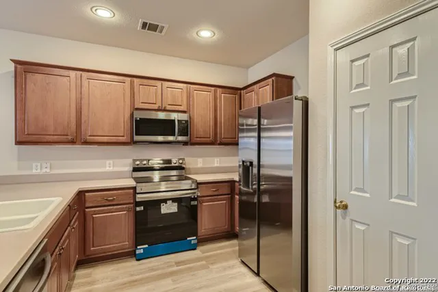 a kitchen with stainless steel appliances granite countertop a stove top oven a sink dishwasher and a microwave oven with large wooden cabinets