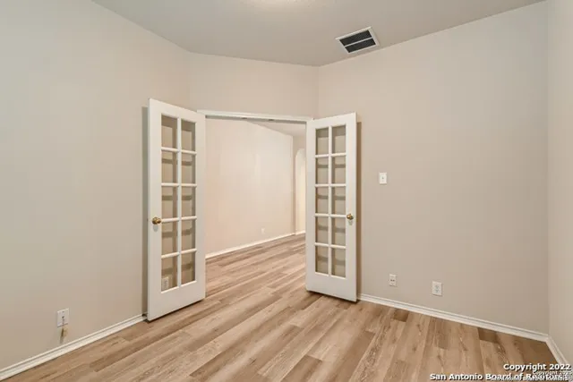 an empty room with wooden floor fan and windows