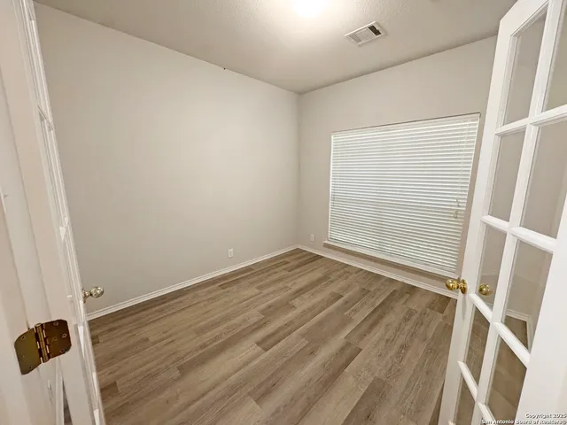 an empty room with wooden floor and windows
