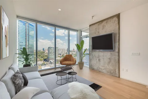 a living room with furniture floor to ceiling window and a flat screen tv