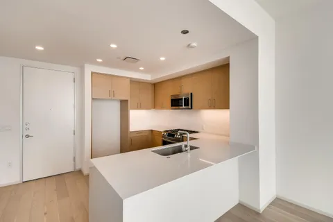 a hallway with a refrigerator a sink and wooden floor