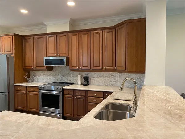 a kitchen with stainless steel appliances granite countertop a sink dishwasher stove and refrigerator with wooden cabinet