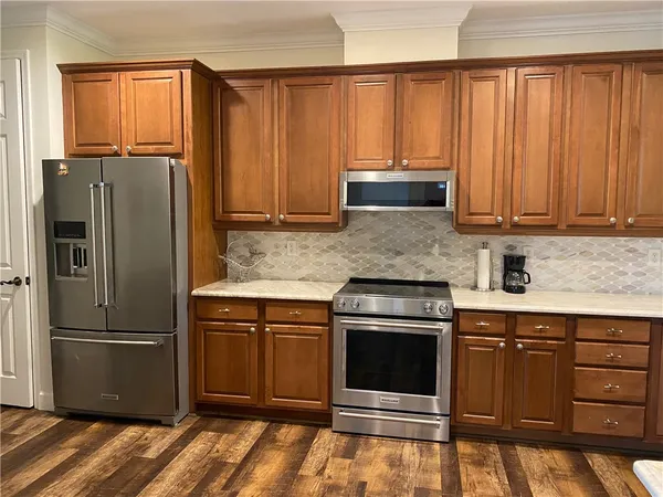 a kitchen with granite countertop a refrigerator stove and cabinets