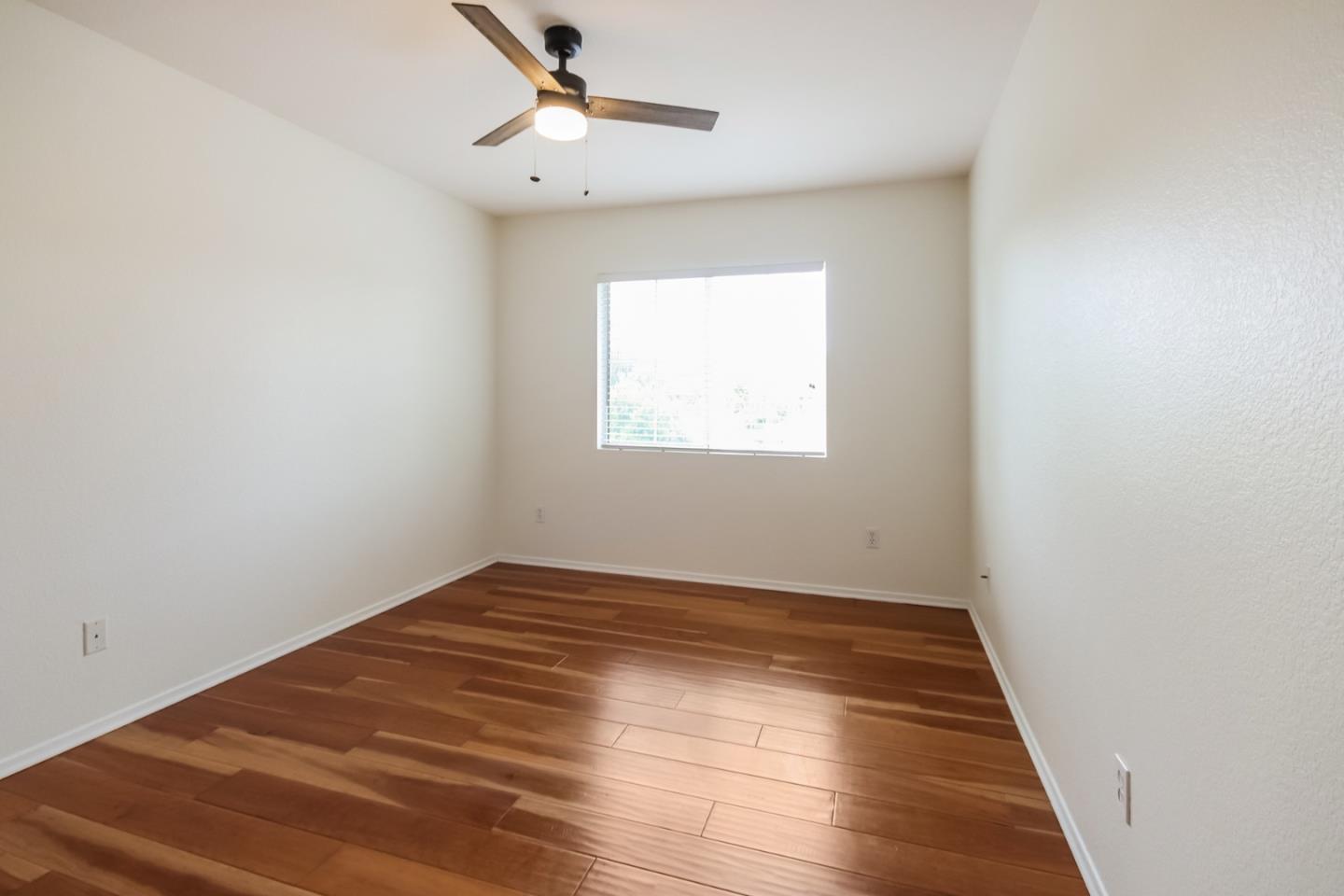 1103 Greenway Road Oceanside, CA 92057 - Photo 19 of 24 an empty room with wooden floor chandelier fan and windows