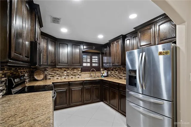 a kitchen with stainless steel appliances granite countertop a refrigerator a stove and a sink