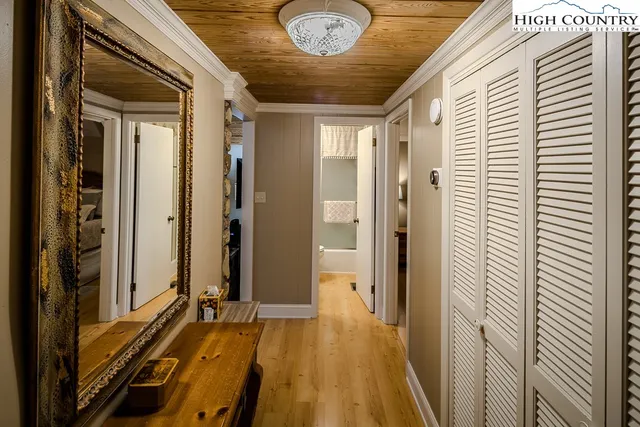 a view of a hallway with wooden floor and a bathroom