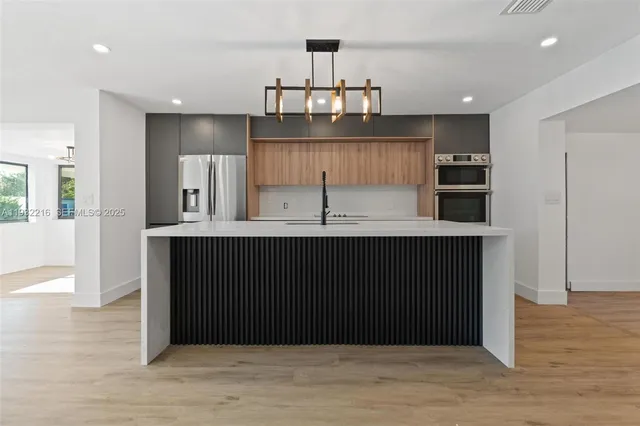 a kitchen with kitchen island granite countertop a refrigerator and cabinets