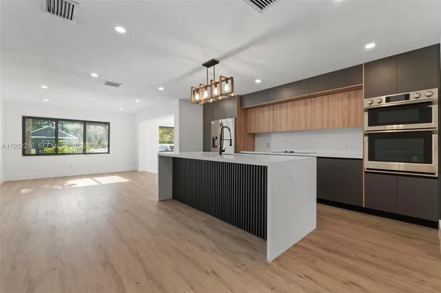 a kitchen with kitchen island granite countertop a sink cabinets and stainless steel appliances