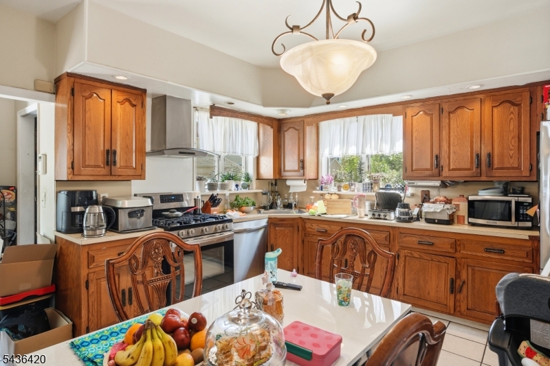 33 Pulaski Place Hackensack, NJ 07601 - Photo 12 of 31 a kitchen with stainless steel appliances kitchen island granite countertop a sink dishwasher a stove a dining table and chairs with wooden floor