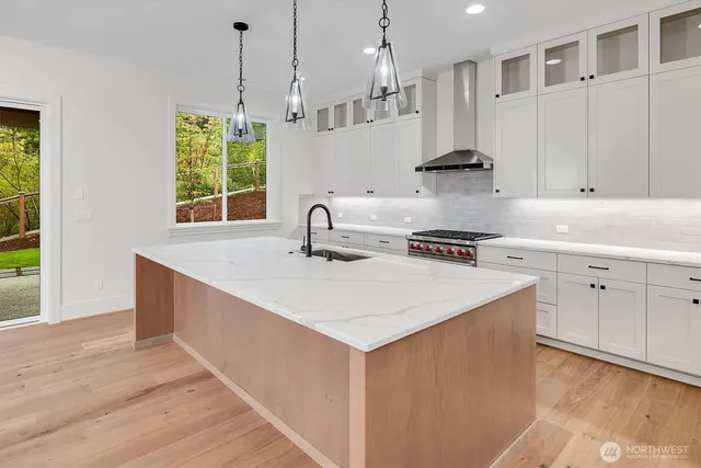 a kitchen with stainless steel appliances granite countertop a sink a stove and a wooden floors