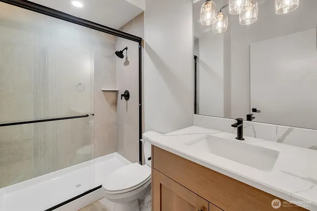 a bathroom with a sink a mirror a toilet and shower