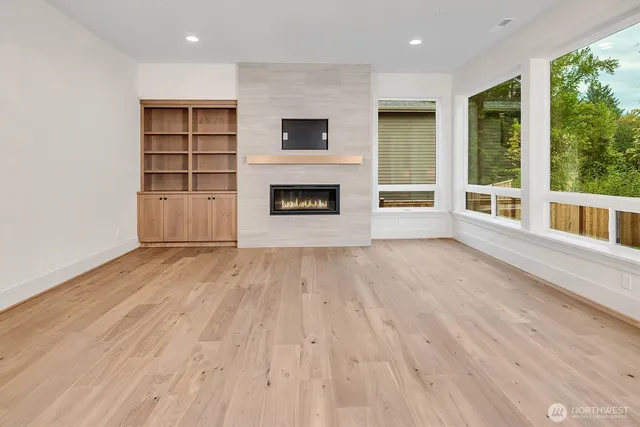 an empty room with wooden floor fireplace and windows