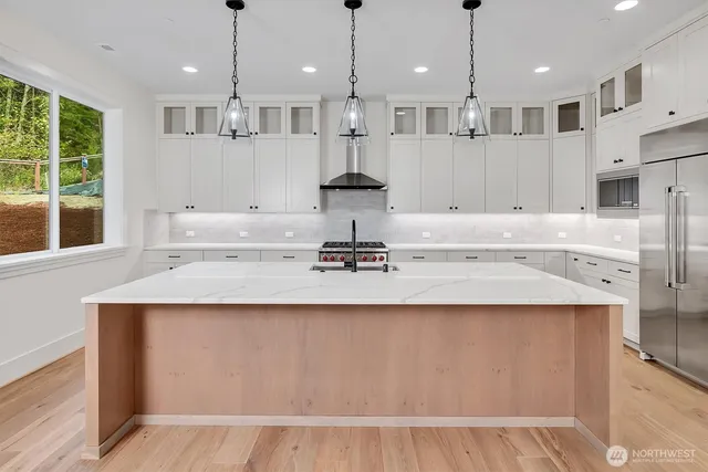 a kitchen with kitchen island granite countertop a sink a center island stainless steel appliances and a window