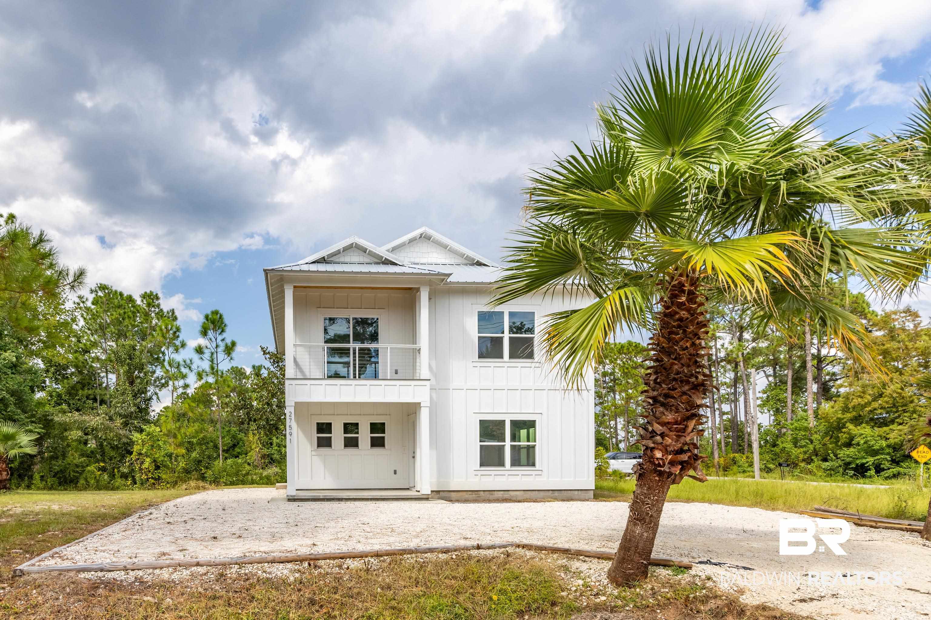 27591 Canal Road Orange Beach, AL 36561 - Photo 3 of 51 View of front facade with a balcony, a patio area, board and batten siding, and gravel driveway
