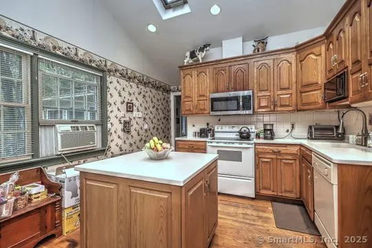 a kitchen with stainless steel appliances granite countertop a stove a sink dishwasher and a refrigerator with wooden cabinets