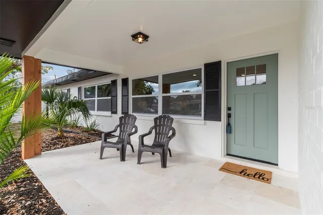 a patio with table and chairs and potted plants