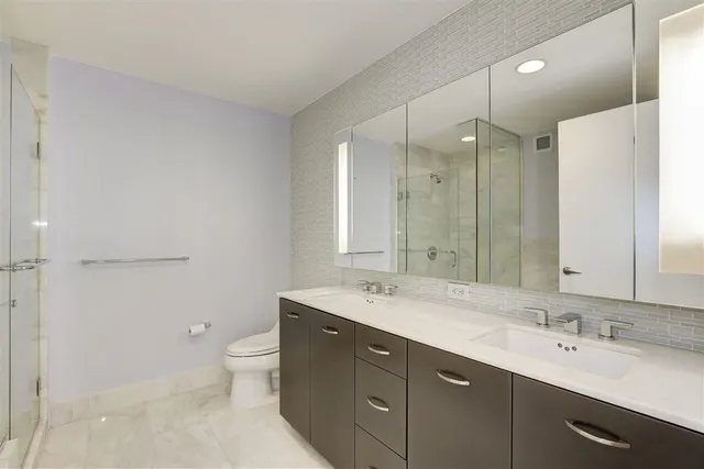 a bathroom with a double vanity sink mirror and toilet