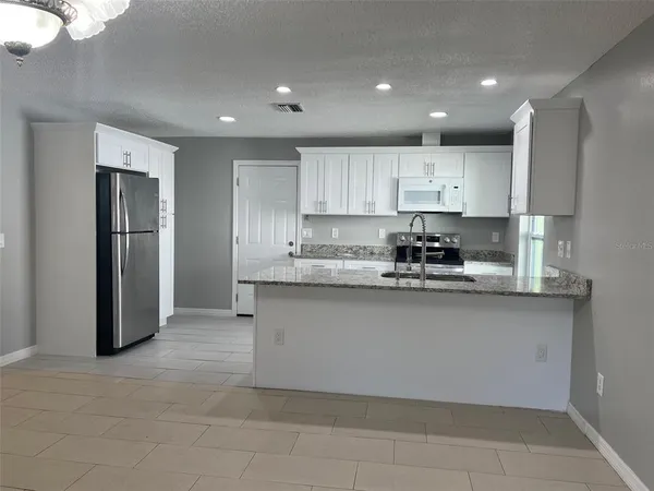 a kitchen with stainless steel appliances granite countertop a refrigerator a sink and a stove