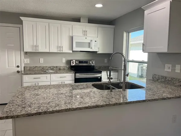 a kitchen with granite countertop a sink a stove and cabinets