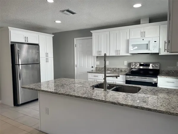 a kitchen with stainless steel appliances granite countertop a sink a refrigerator and a granite counter tops