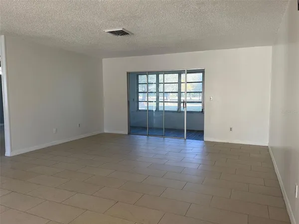 an empty room with chandelier fan and windows