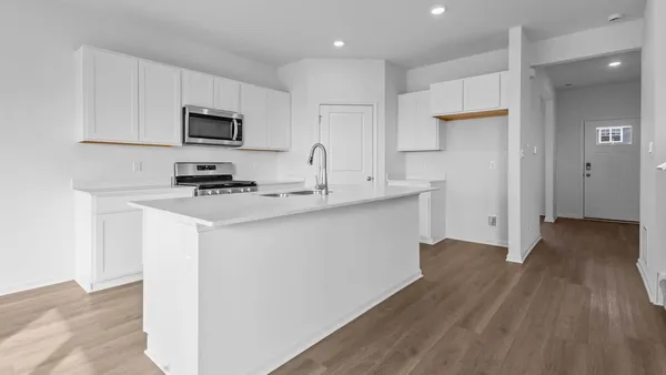 a kitchen with stainless steel appliances a wooden floor a stove a sink and a refrigerator