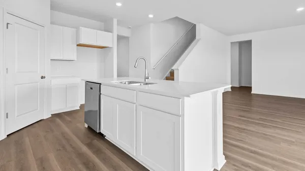 a view of a kitchen with white cabinets and wooden floor