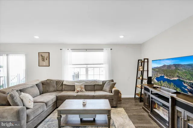 a living room with furniture a flat screen tv and a floor to ceiling window