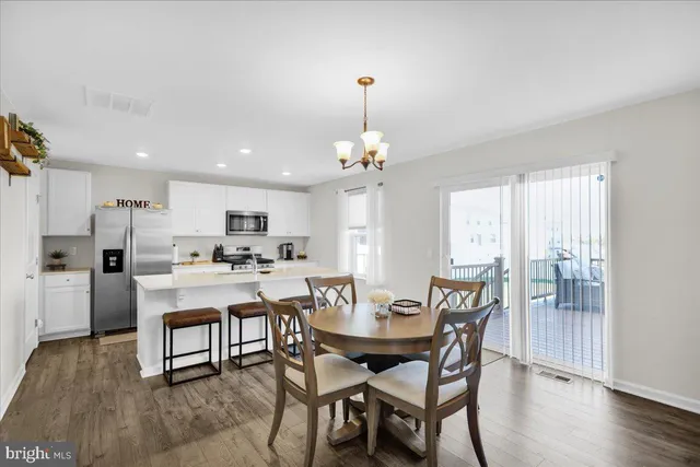 a dining room with wooden floor a chandelier a wooden table and chairs