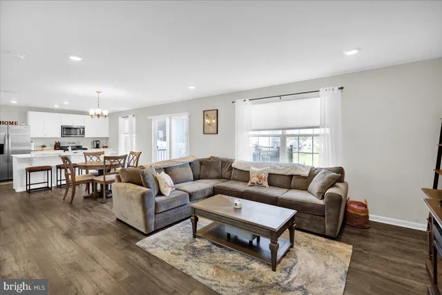 a living room with furniture kitchen view and a window