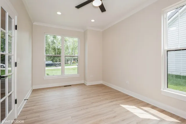 an empty room with wooden floor cabinet and windows
