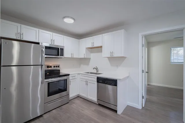 a kitchen with stainless steel appliances a sink dishwasher a refrigerator and a stove with wooden floor