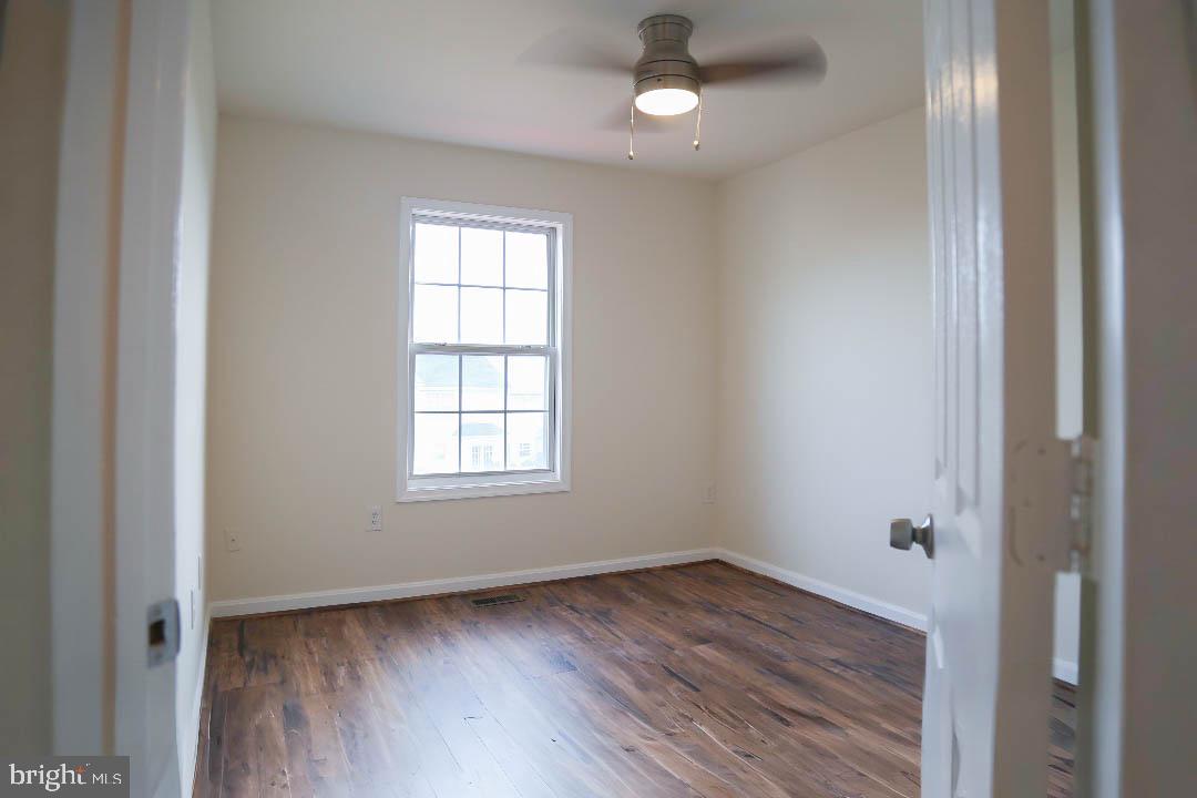 8461 Tackhouse Loop Gainesville, VA 20155 - Photo 8 of 10 an empty room with wooden floor cabinet and windows