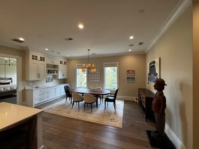 a view of dining room and livingroom with furniture wooden floor a rug a painting and a chandelier