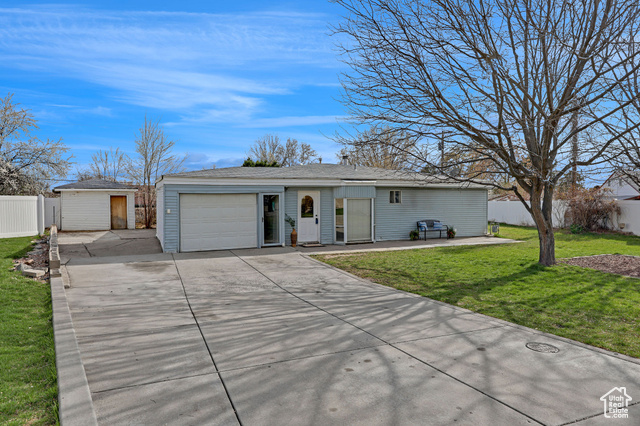 Ranch-style home with a front yard, driveway, fence, and a garage