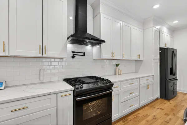 a kitchen with stainless steel appliances granite countertop a stove a refrigerator and a white cabinets