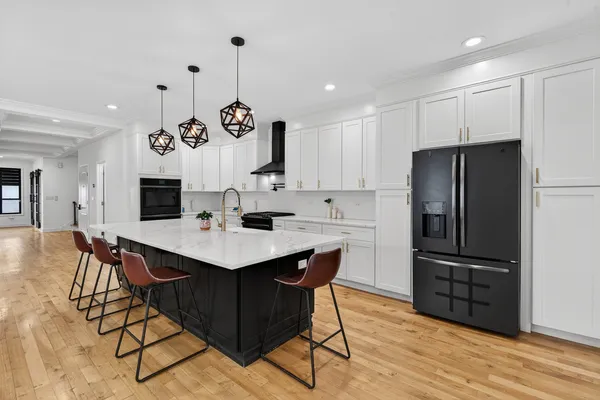 a kitchen with stainless steel appliances granite countertop a refrigerator a sink dishwasher a stove and a refrigerator with wooden floor