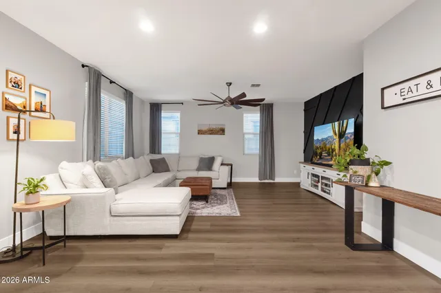 a kitchen with granite countertop a refrigerator a stove a sink and chairs with wooden floor