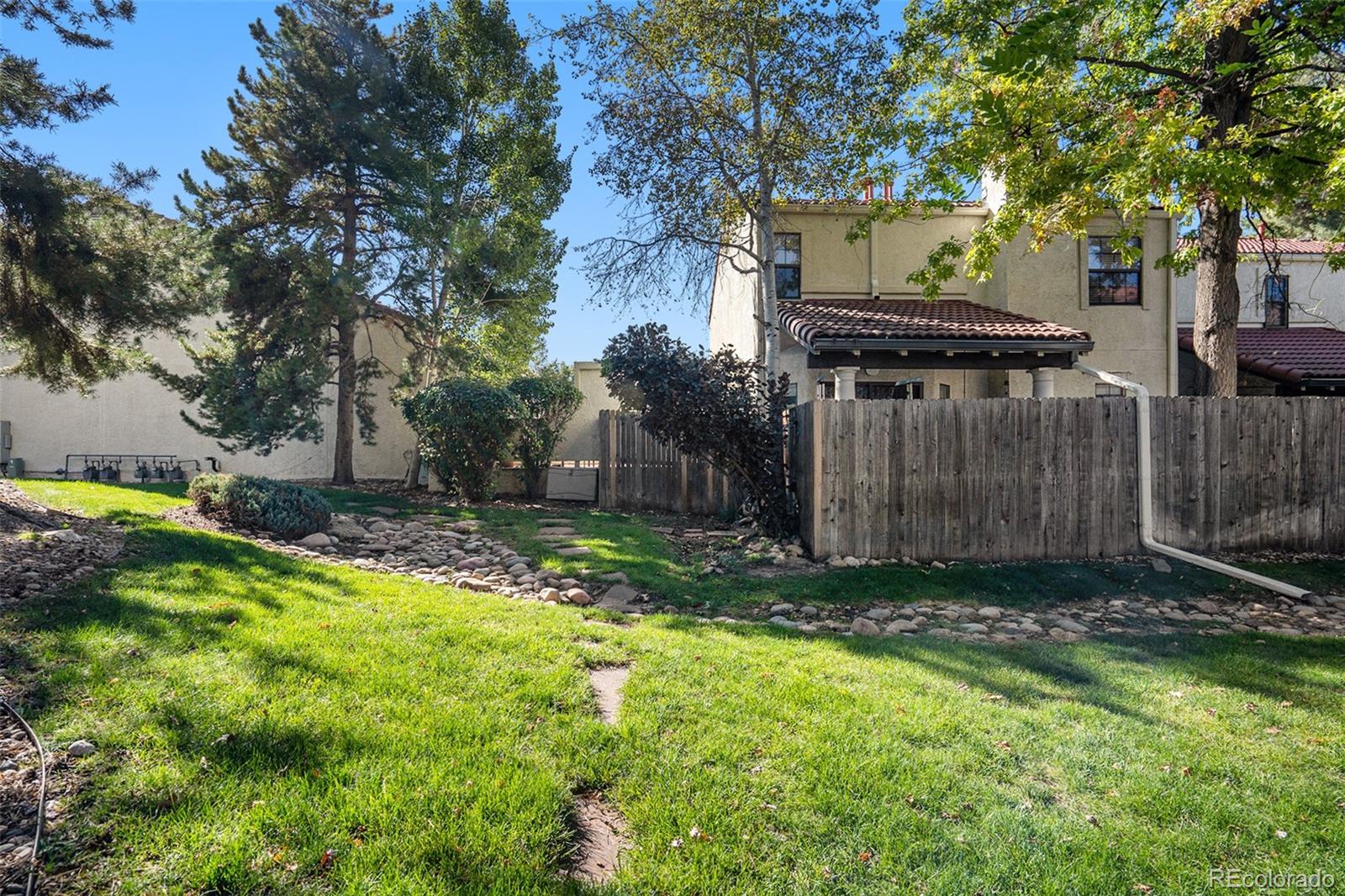 1600 South Quebec Way, Unit 10 Denver, CO 80231 - Photo 28 of 29 a view of a backyard with wooden fence and a large tree