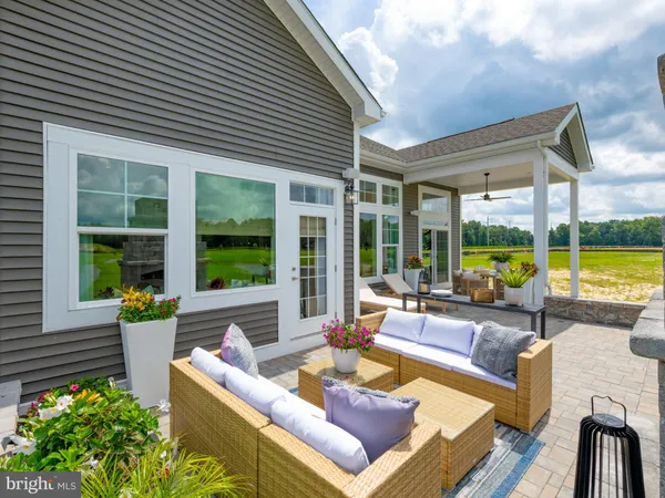 a view of a patio with couches chairs potted plants and floor to ceiling window