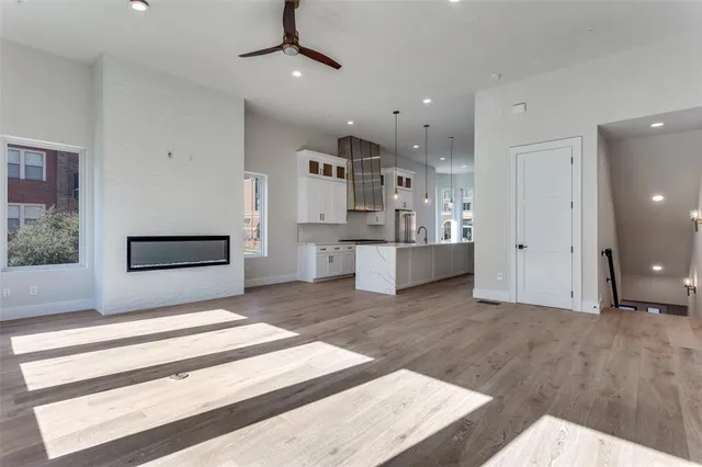 a large white kitchen with kitchen island granite countertop a stove a sink a refrigerator and white cabinets with wooden floor