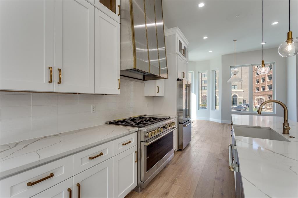 250 East Dallas Road, Unit 114 Grapevine, TX 76051 - Photo 13 of 33 a kitchen with stainless steel appliances granite countertop a sink dishwasher a stove and a refrigerator with wooden floor