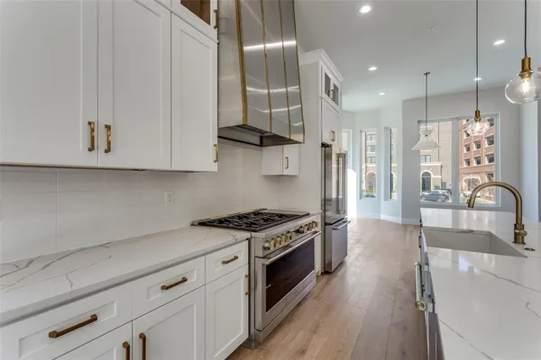 a large kitchen with kitchen island a stove a sink a refrigerator and a wooden floor