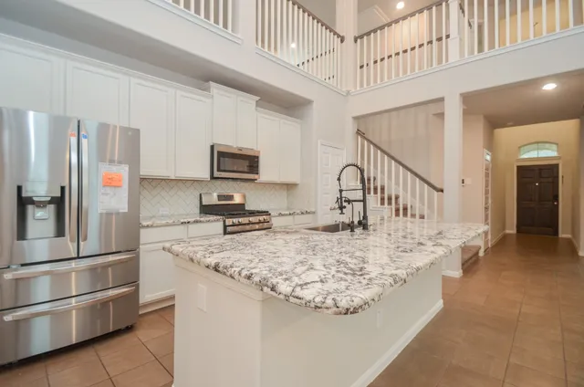 a kitchen with stainless steel appliances granite countertop a refrigerator a stove a sink and a refrigerator