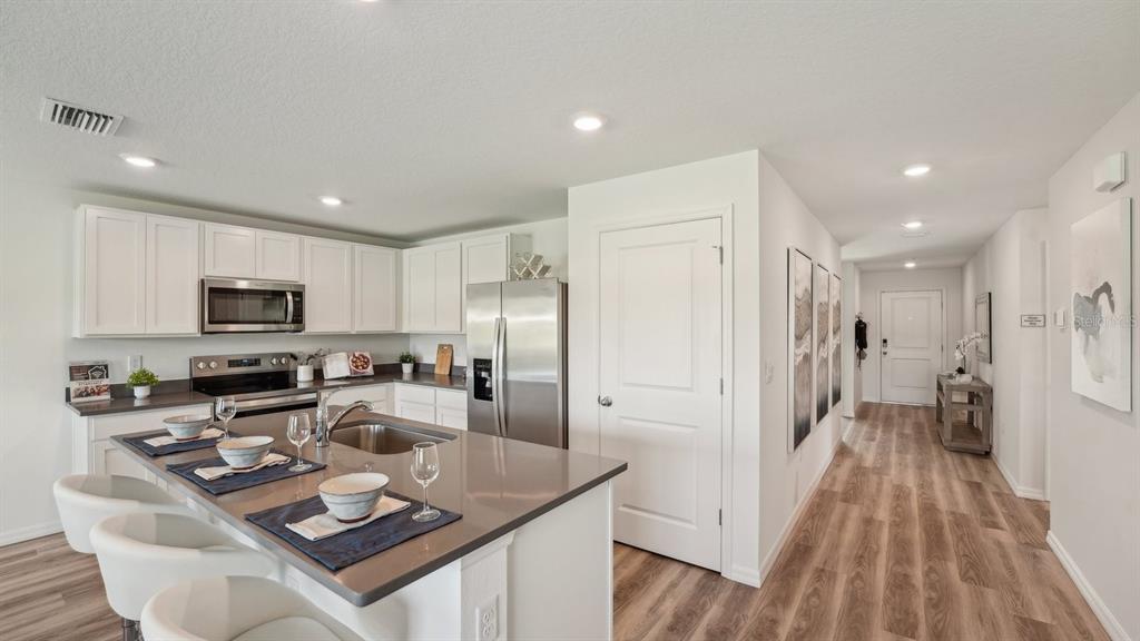 15898 Southeast 101st Ct Road Summerfield, FL 34491 - Photo 3 of 29 a kitchen with stainless steel appliances granite countertop a refrigerator a stove a sink a dining table and chairs with wooden floor